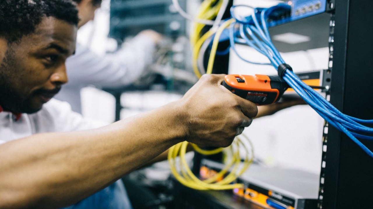 Technician servicing cabling inside a network rack