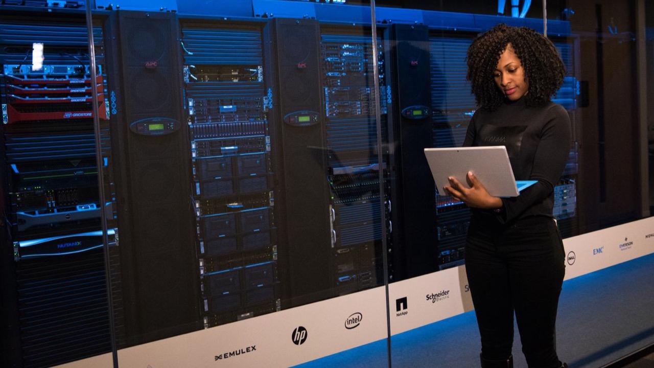 Engineer reviewing network status on a laptop beside the racks